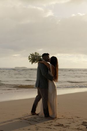 A romantic sunset beach elopement moment with waves crashing in the background.