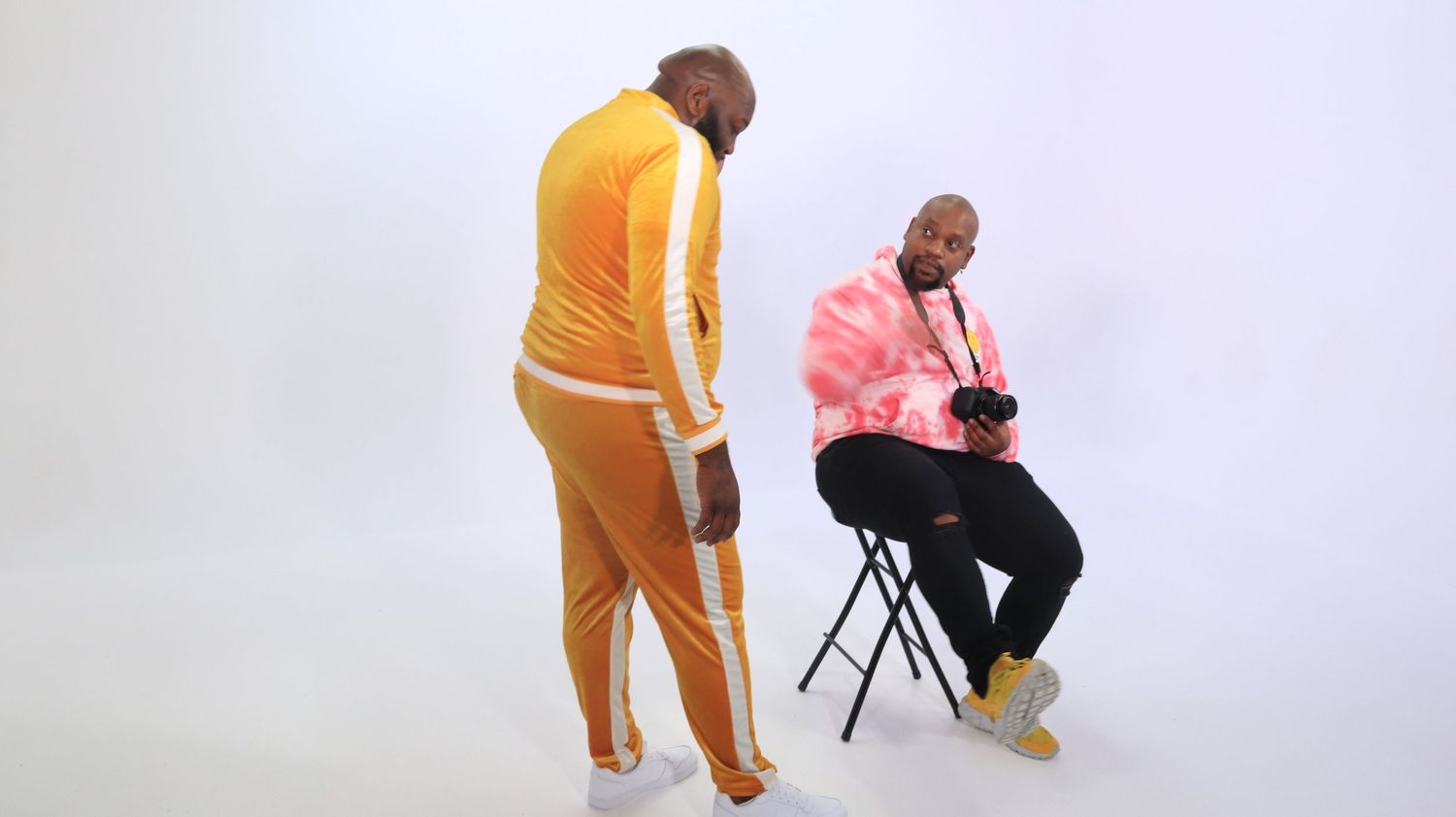 Two people in casual clothing during a photo shoot against white background.