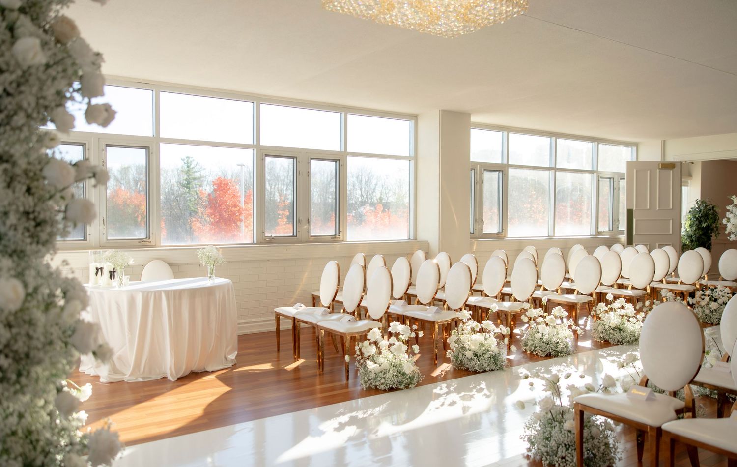 Wedding ceremony space with white chairs and large windows offering natural light.