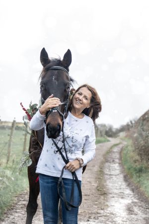 Black horse and companion walking together on a country path with holiday decorations.