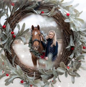 Festive holiday portrait through decorative wreath with horse wearing seasonal garland.