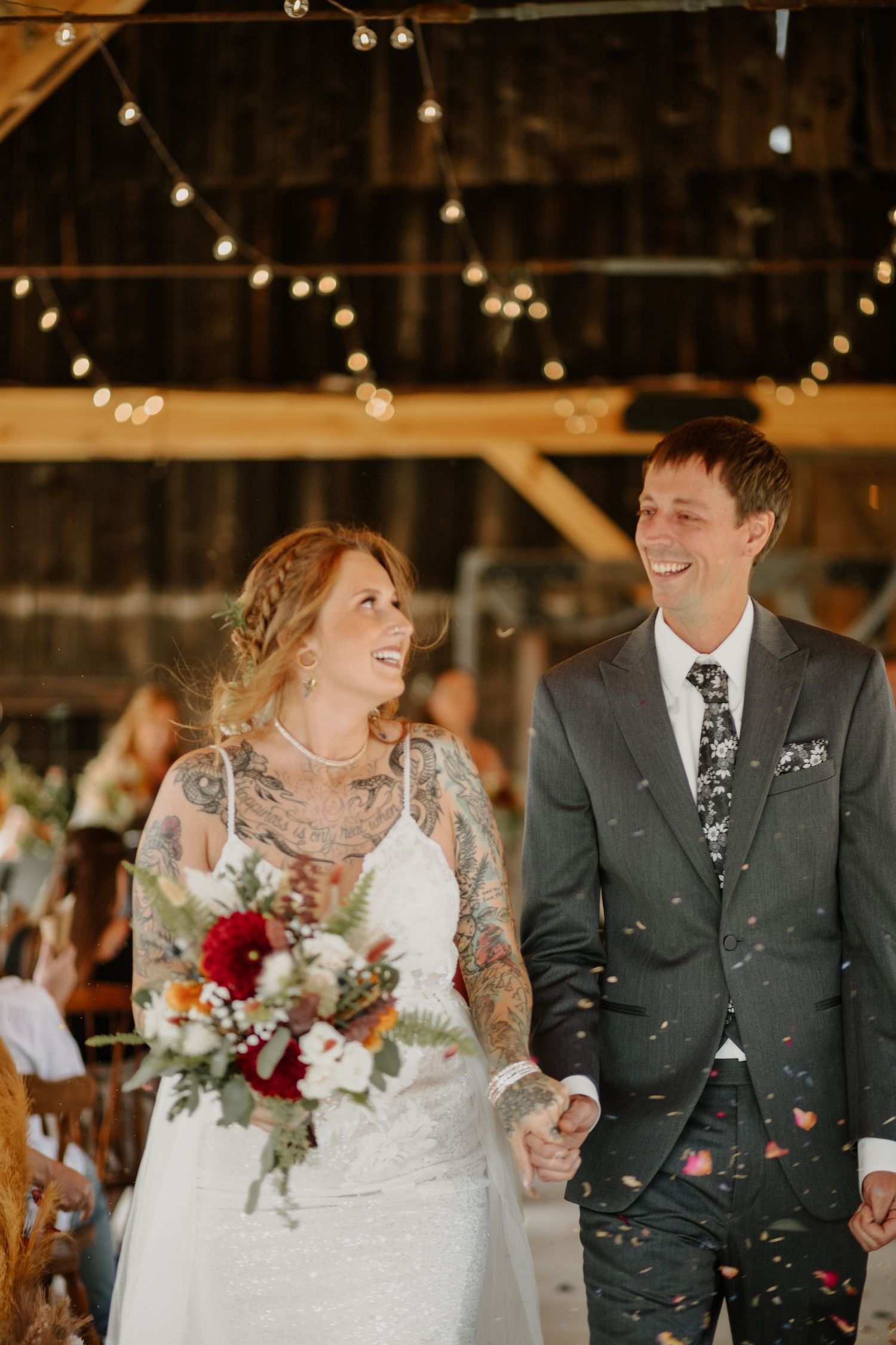 A joyful wedding celebration in a rustic barn with string lights and confetti.