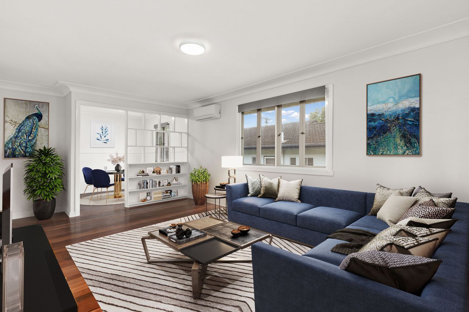 Spacious formal lounge with blue sofas, hardwood floors, built-in shelving, and large garden-view window.