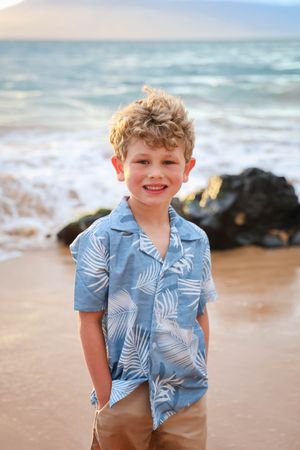 A series of beach portraits showing a young child in a blue tropical print shirt against an ocean backdrop.