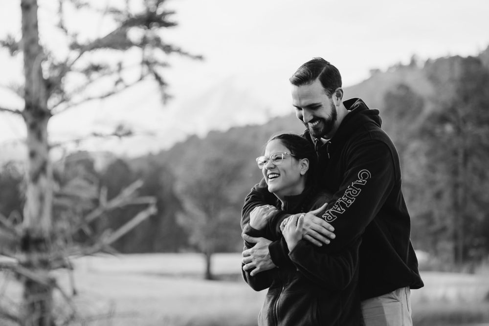 A romantic black and white photo series showing a couple embracing and laughing together outdoors in nature.