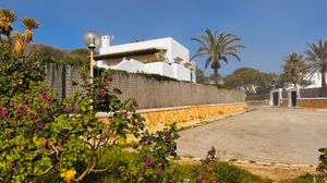 Mediterranean style villa with white walls and palm trees along a sunny coastal path in Spain.