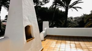 White stucco terrace with terra cotta tiles and palm trees features a built-in alcove on a Mediterranean-style patio.