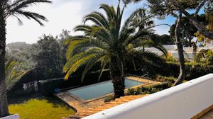 Wide panoramic shot of a coastal property with white walls, palm trees and ocean views.