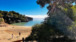 Panoramic view of a scenic coastal landscape with rocky cliffs, blue ocean waters and lush green vegetation.