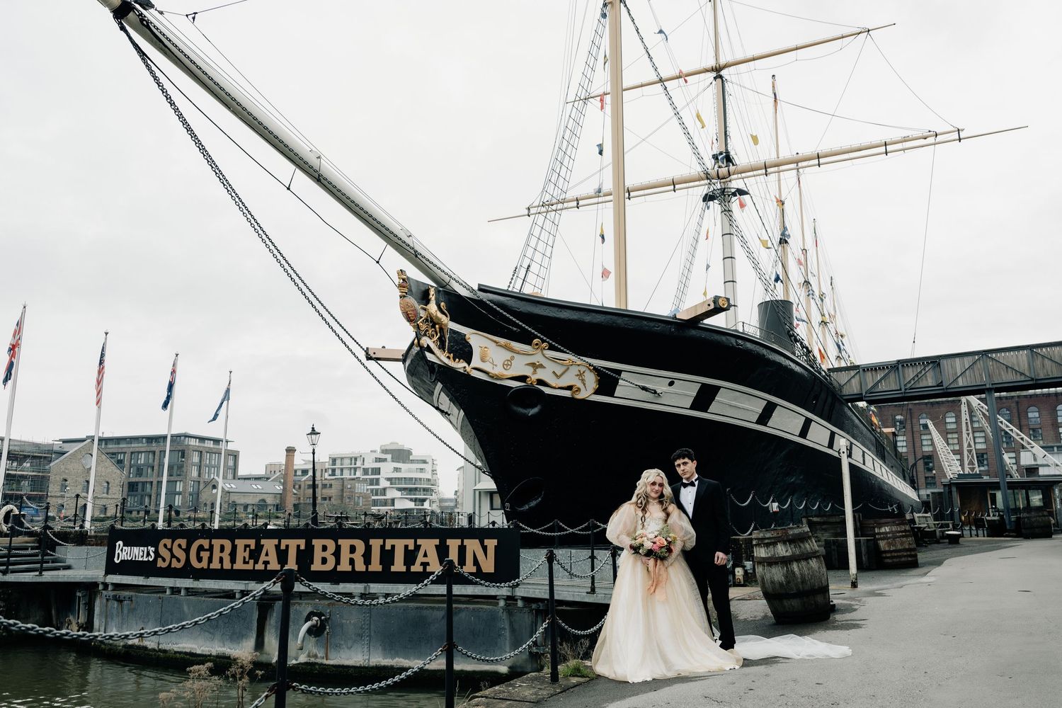 Historic tall ships with white sails are moored at a dock during a maritime festival display.
