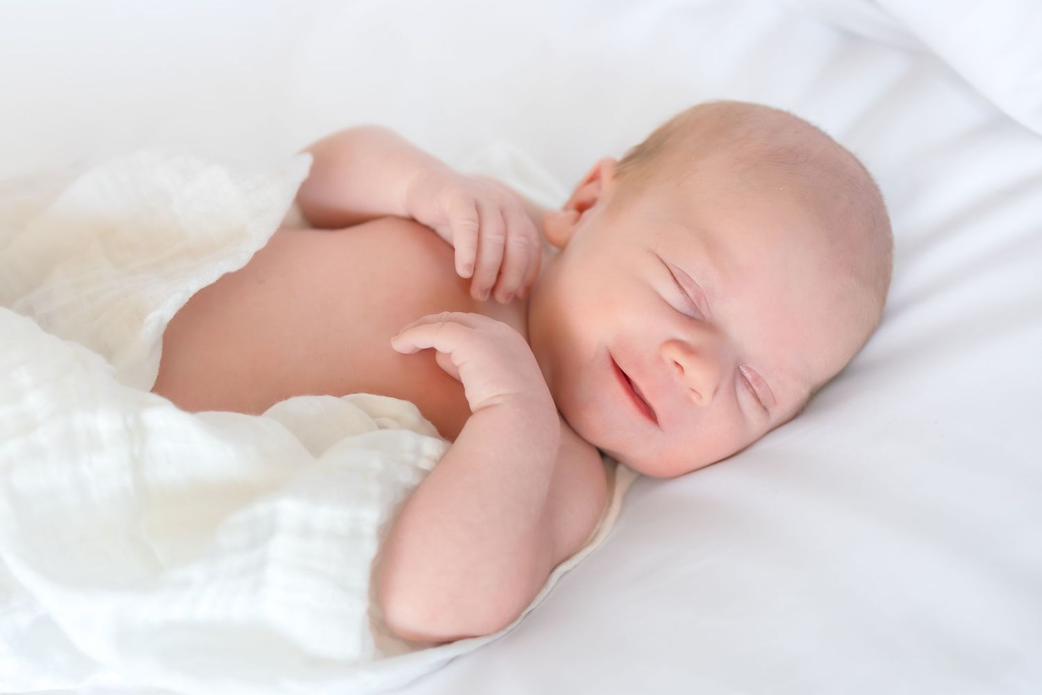 Newborn baby sleeping on white blanket during an in-home lifestyle newborn photography session  near Athens GA.