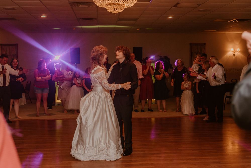 Wedding reception ballroom with purple lighting and couples dancing.