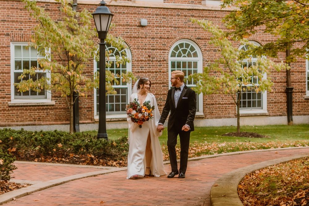 Autumn wedding scene with brick building and fall foliage in background.