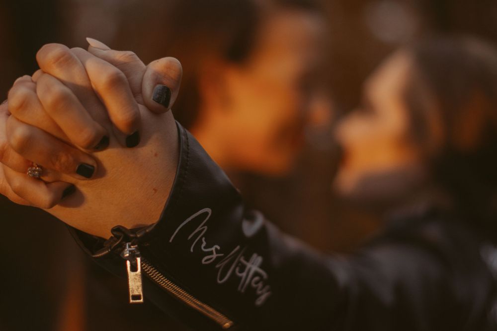 Hands holding leather jackets in warm autumn lighting.