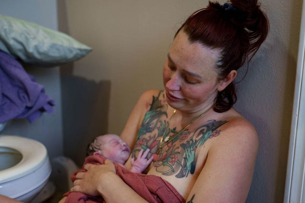 A tender moment between parent and newborn baby in a dimly lit room.