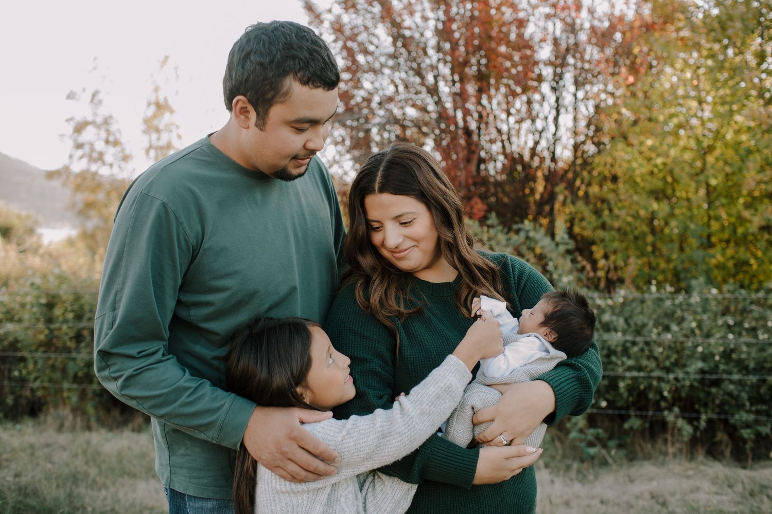 A family sharing a tender moment together outdoors during golden hour.