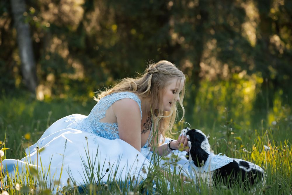 People in formal blue and white attire sitting casually on grass during outdoor photo session.