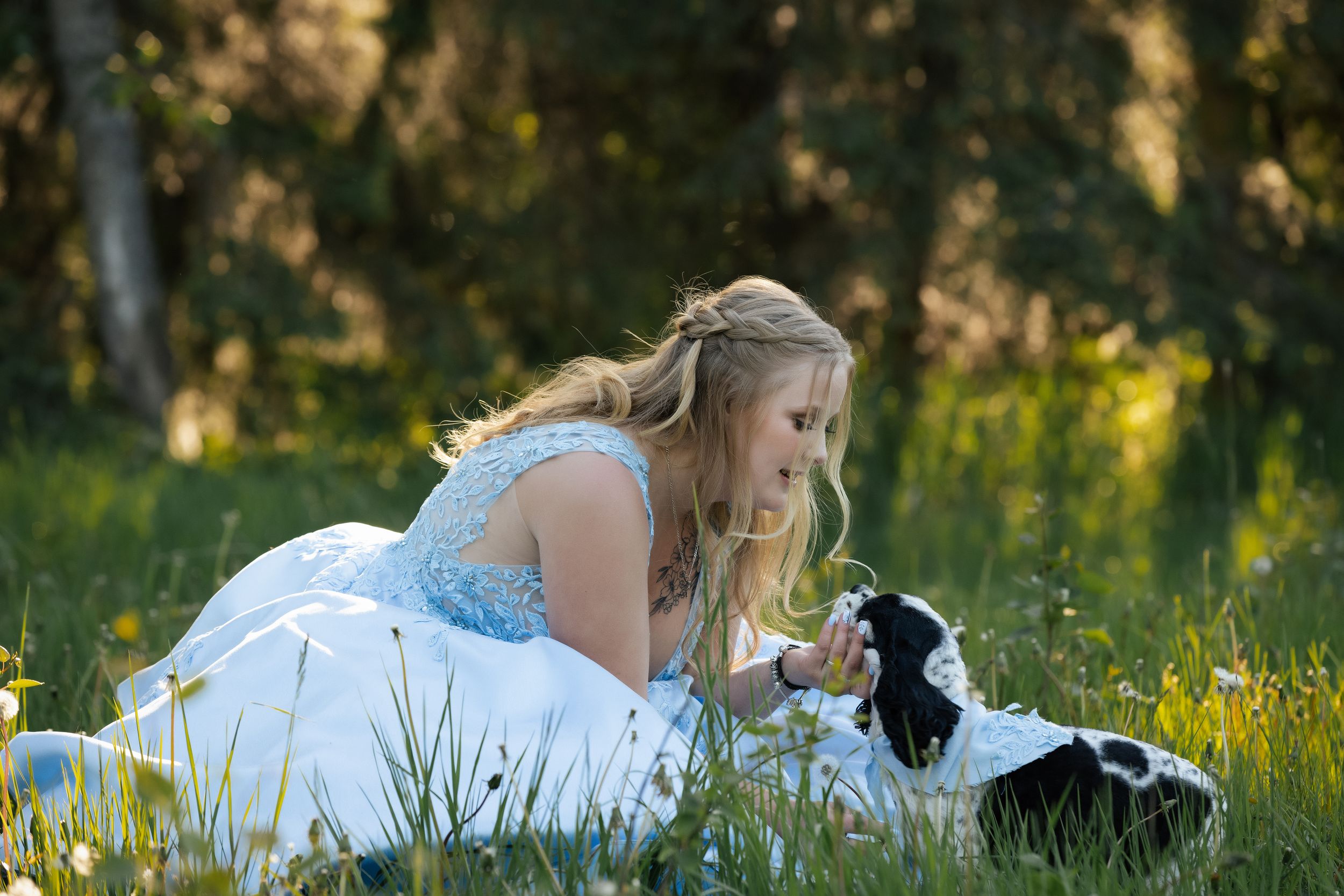 People in formal blue and white attire sitting casually on grass during outdoor photo session.