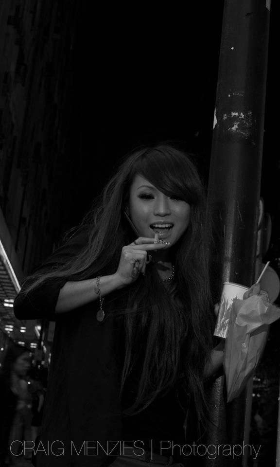 Smiling young woman with long hair posing on a dark street in black and white photography.