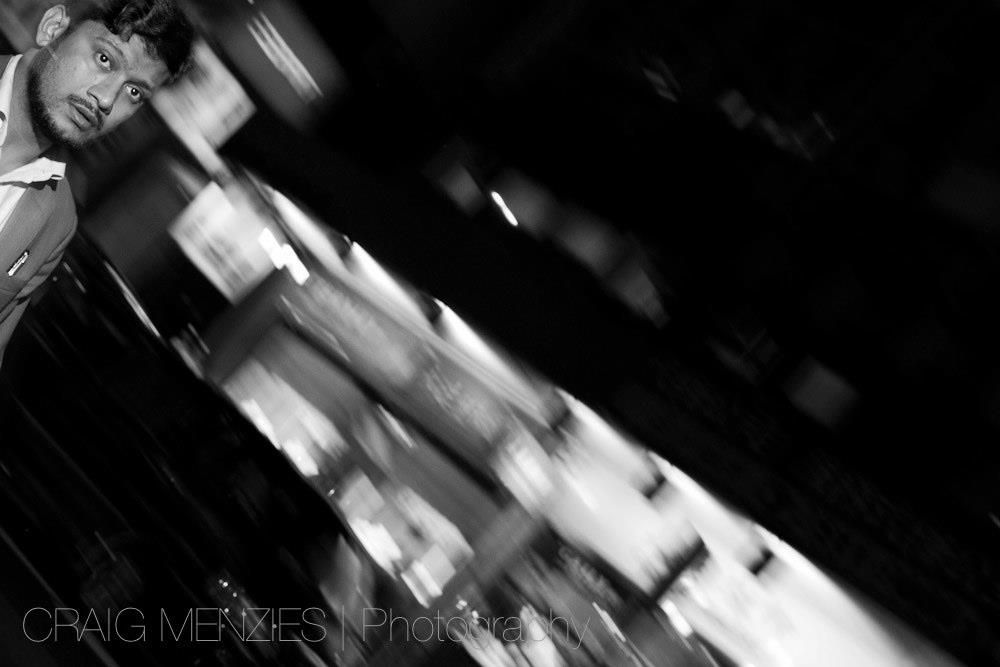 Black and white blurred street photo of a man walking at night.