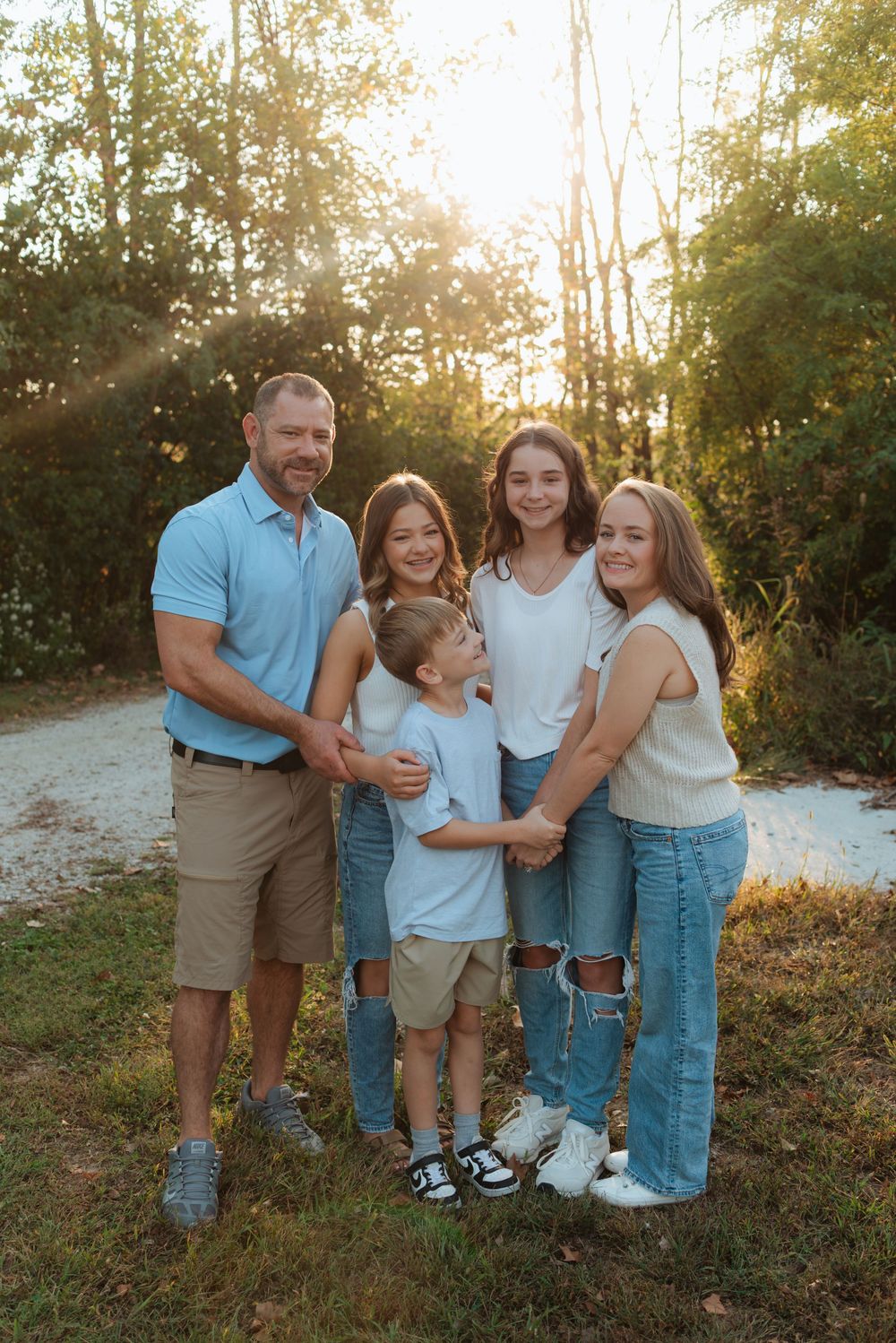 Casual family portrait session in coordinating blue and white outfits during sunset.