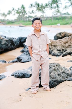 A joyful scene on a rocky beach with palm trees in the background and light beige clothing.
