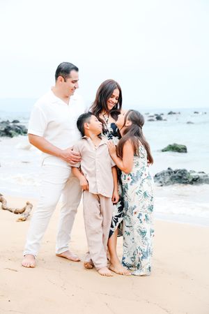 Family group shares joyful moments together on a sandy beach during a tropical photoshoot.