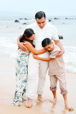 A family plays together in the shallow ocean waves at a tropical beach setting.