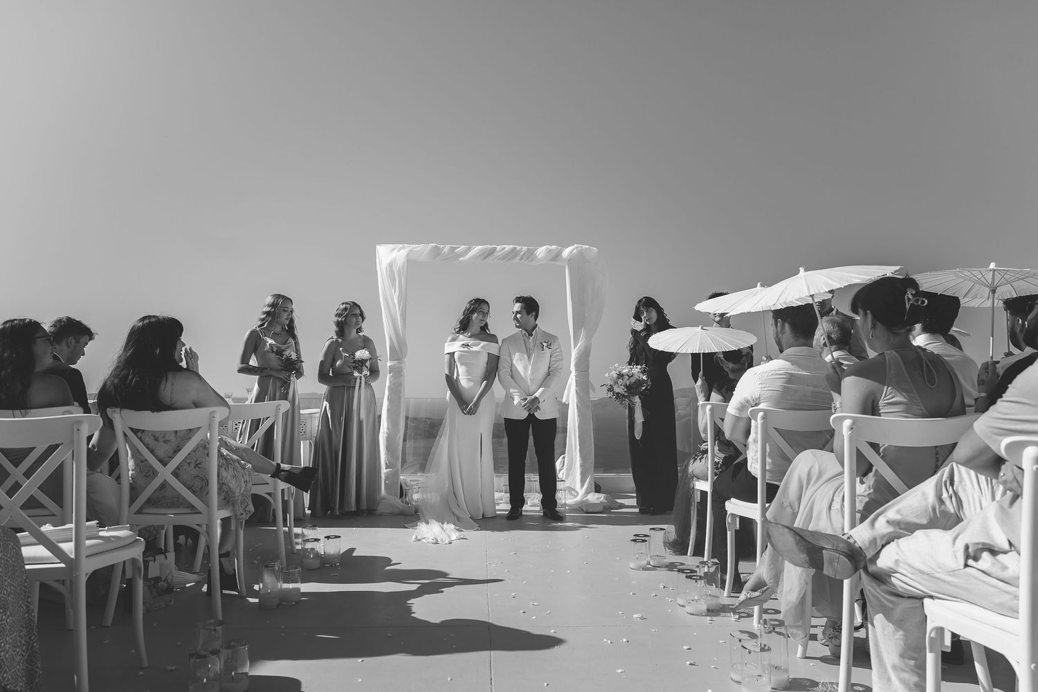 An outdoor destination wedding in Santorini as the couple face each other that the alter and sky as a backdrop.