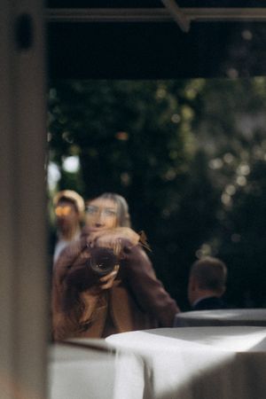Valokuvaaja Polina Khanteeva näkyy ikkunan heijastuksesta Mustion linnassa ja pitelee kameraa käsissään.