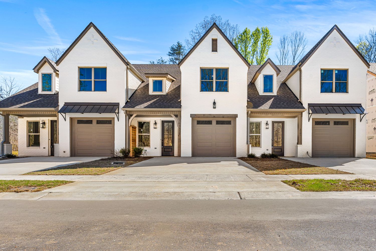 Modern townhouse-style homes with attached garages and white exterior finish.