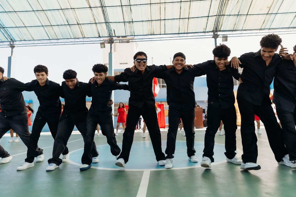 Row of people in black pants performing synchronized leg movements in a dance or exercise routine.