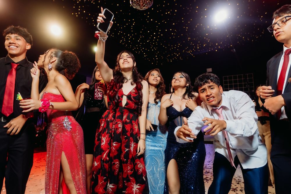 People dance and celebrate at a lively party with dramatic lighting and festive atmosphere.