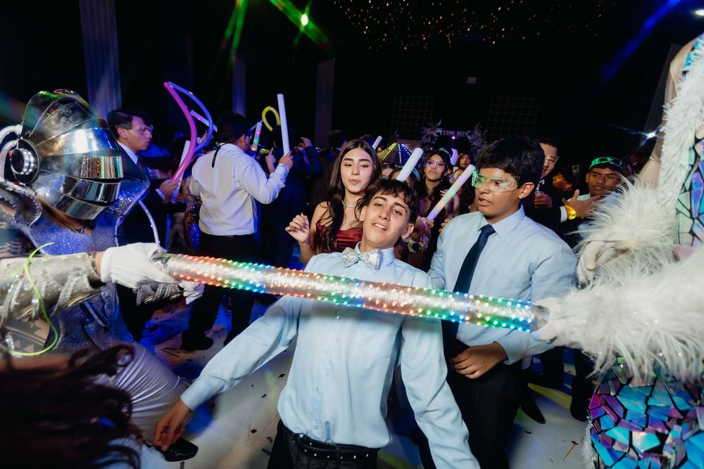 Festive party scene with people dancing under colorful lights while confetti and streamers fill the air.