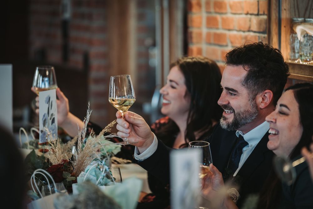 Guests enjoying drinks and conversation at an indoor social gathering with exposed brick walls.