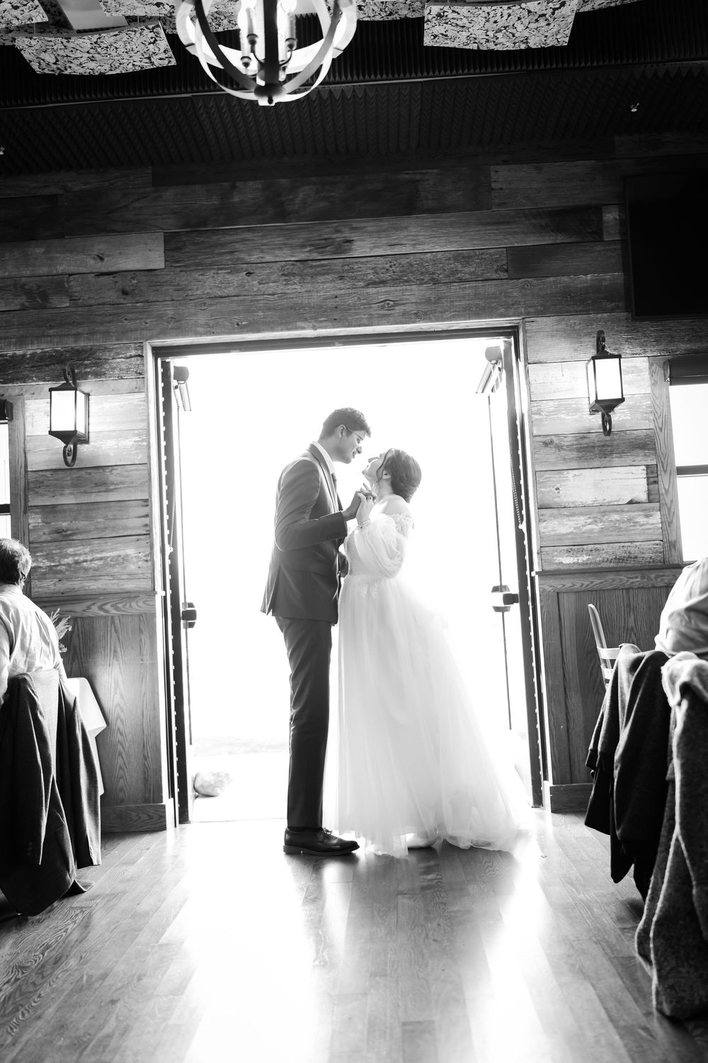 A sequence of black and white photos showing silhouettes of a wedding couple dancing in a rustic wooden room.