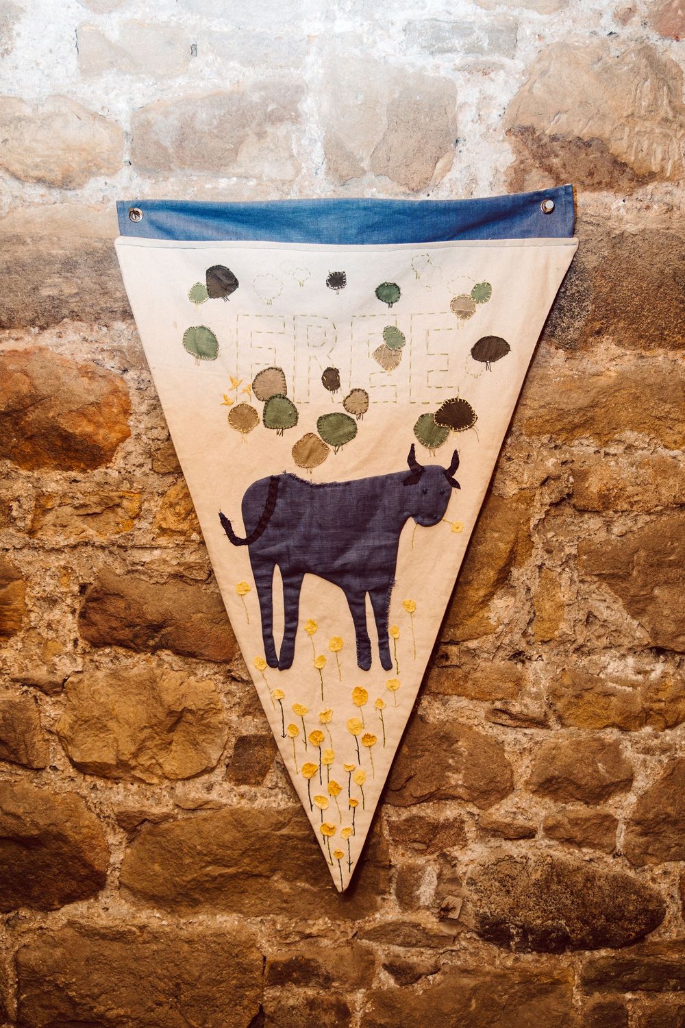 A decorative wall pennant featuring a silhouette of a black cat against a cream background with floating green circles and flowers.