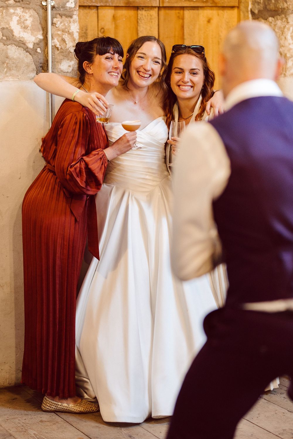 Wedding party members in burgundy dresses and white gown share joyful candid moments during photo session.