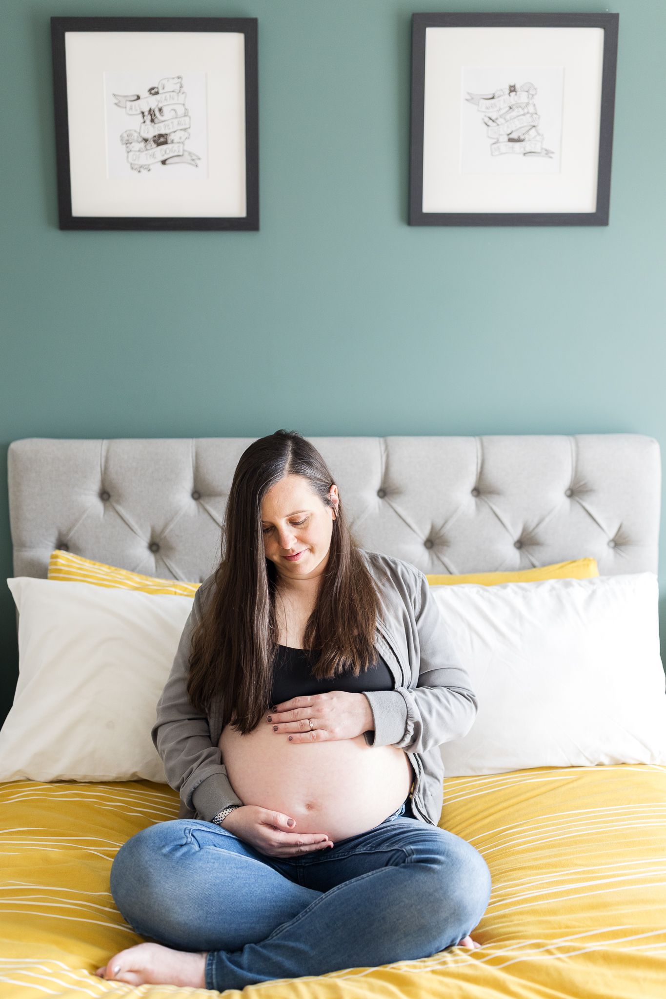 expecting mum sitting on bed holding her pregnant belly