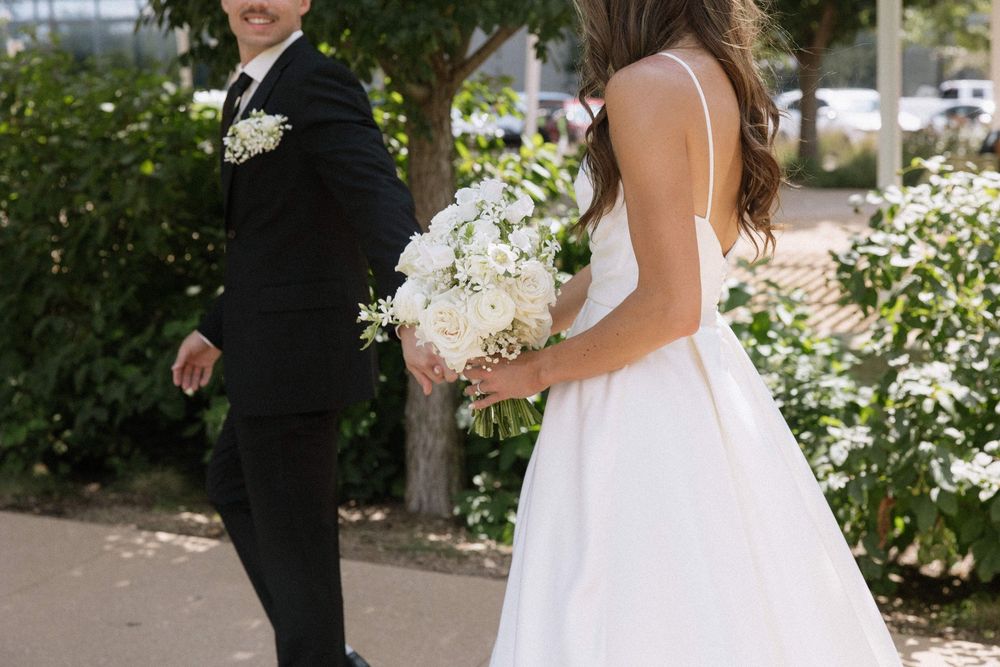 Wedding couple walking outdoors with white floral bouquet.