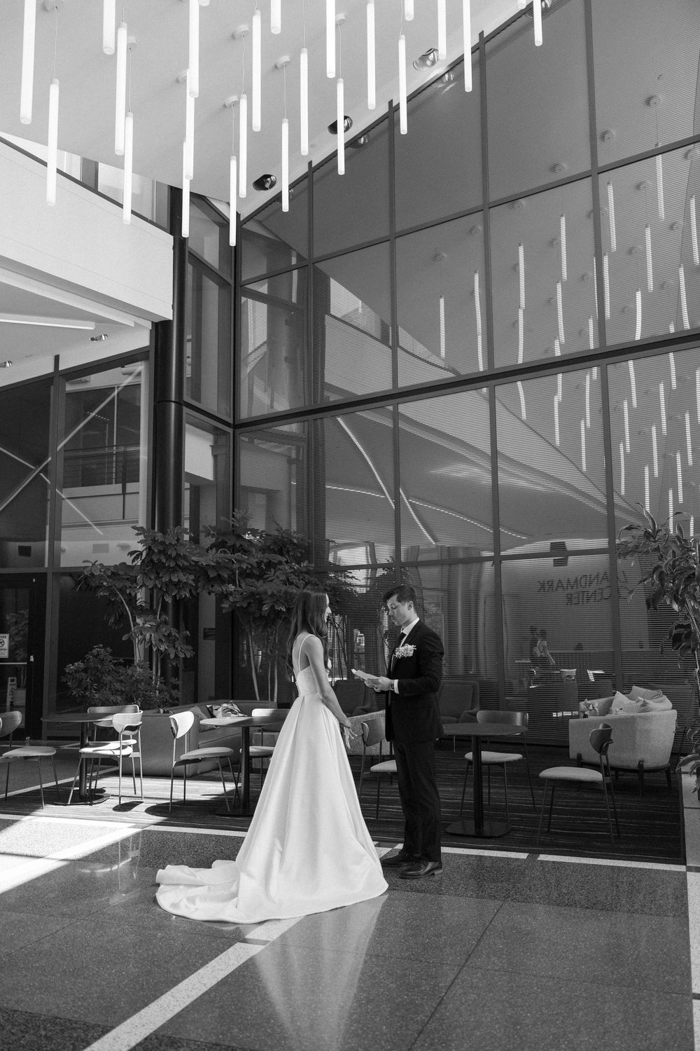 Wedding scene in modern architecture with dramatic lighting and glass walls.