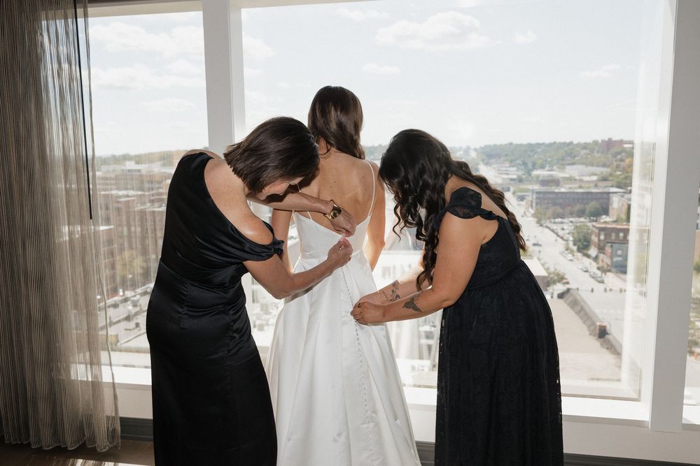 Wedding preparation scene in a bright room with city views.
