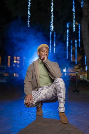 Stylish male portrait at night in Downtown Charleston with dramatic blue lighting and urban background.