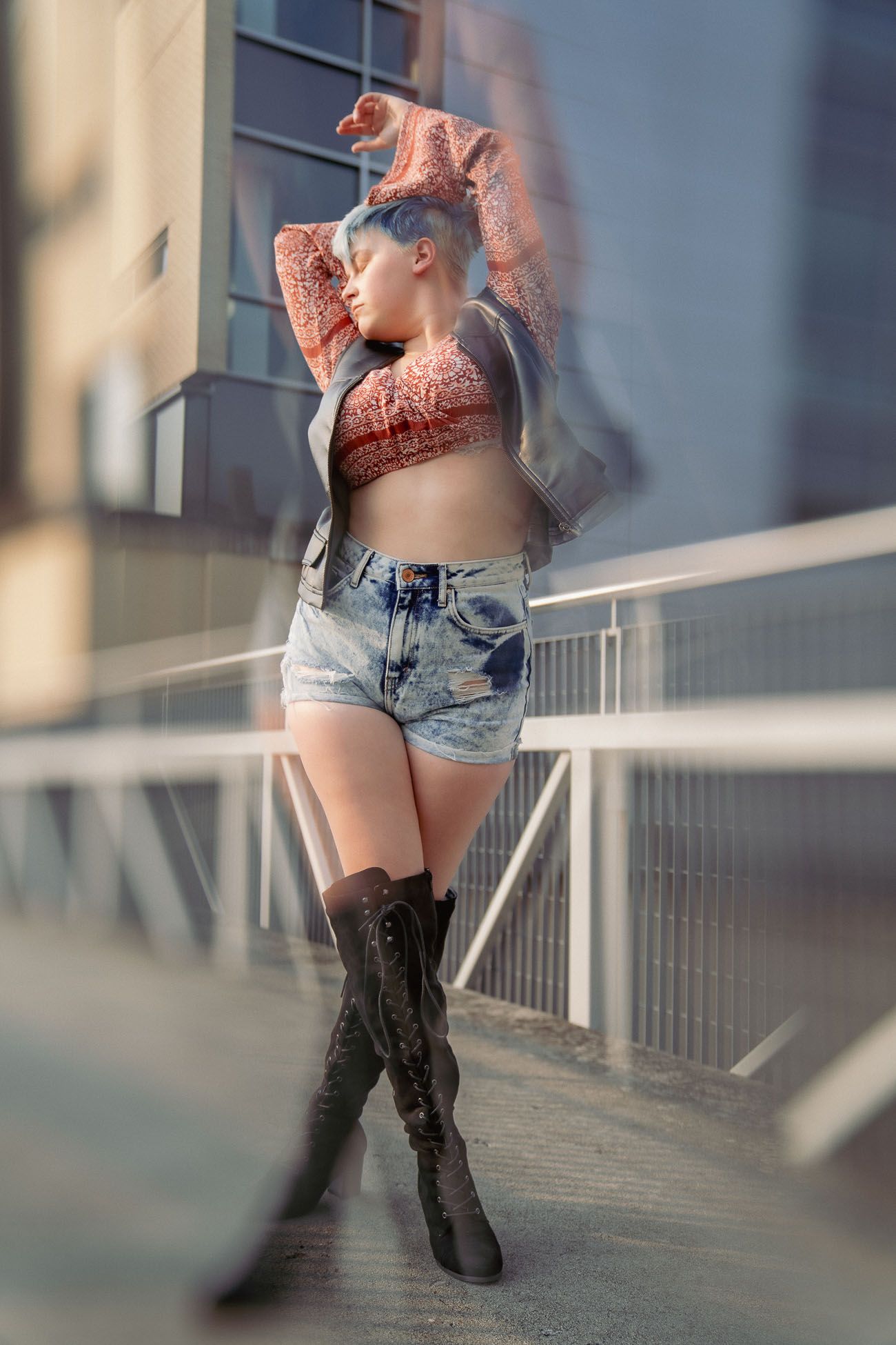 Woman in denim shorts and black boots dances on a balcony in an artistic motion blur sequence in Charleston, SC