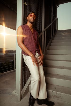 Person wearing burgundy sleeveless shirt and white pants poses on concrete stairwell in Charleston, SC