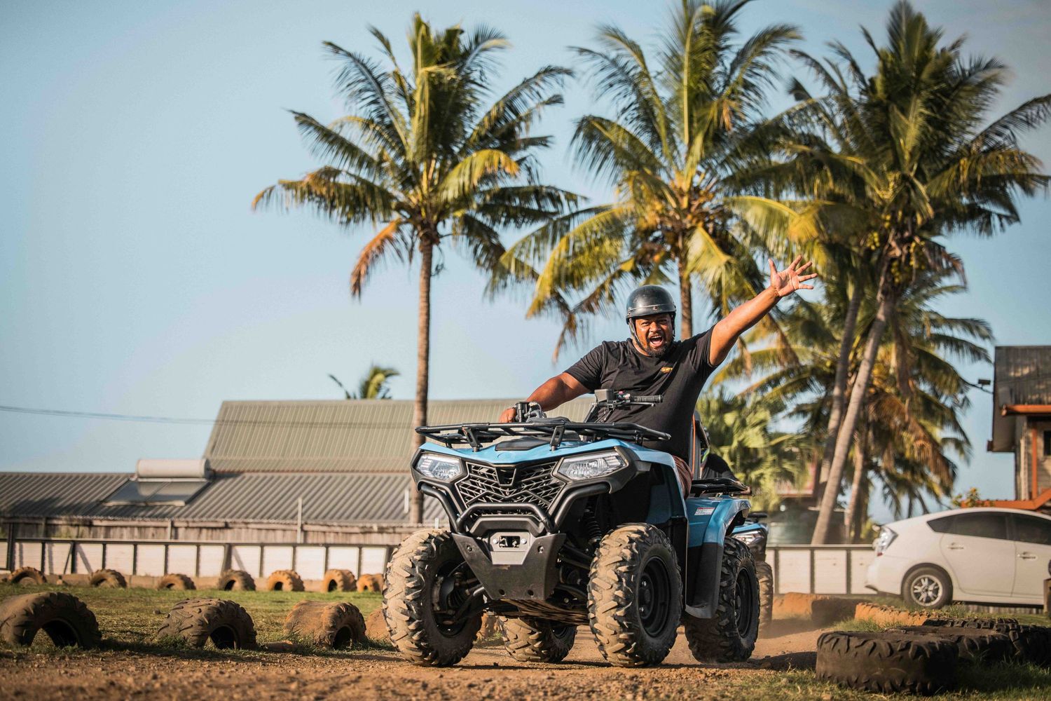 Row of palm trees against sunset sky with ATVs parked beneath them.