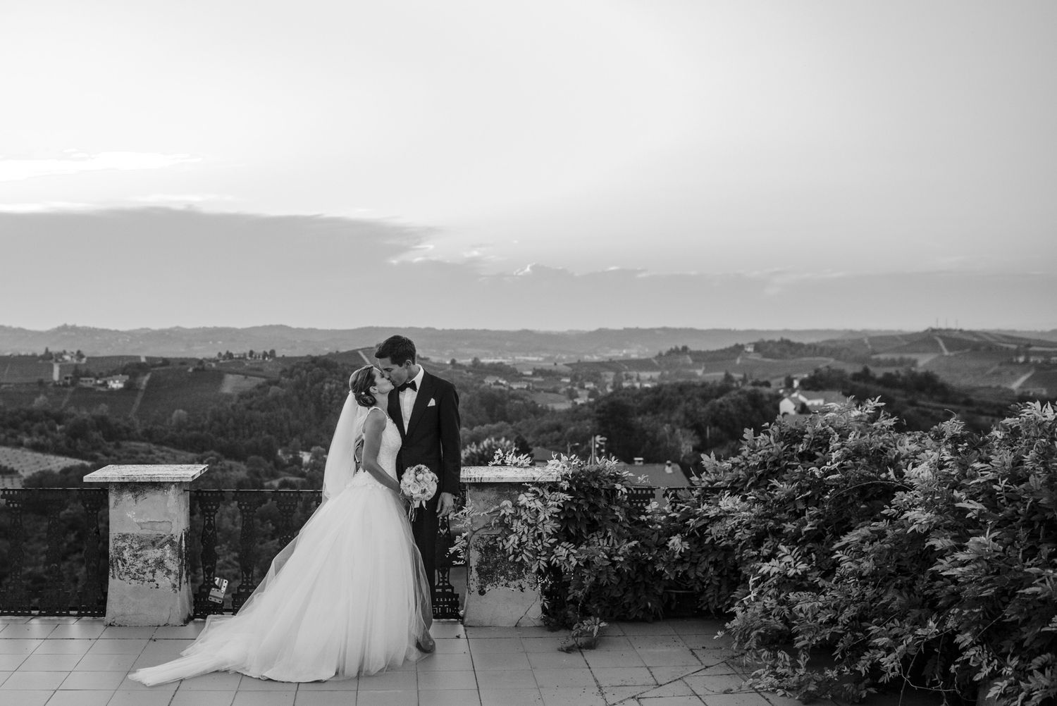 Bride and groom kissing at terrace of la villa hotel mombaruzzo in piedmont