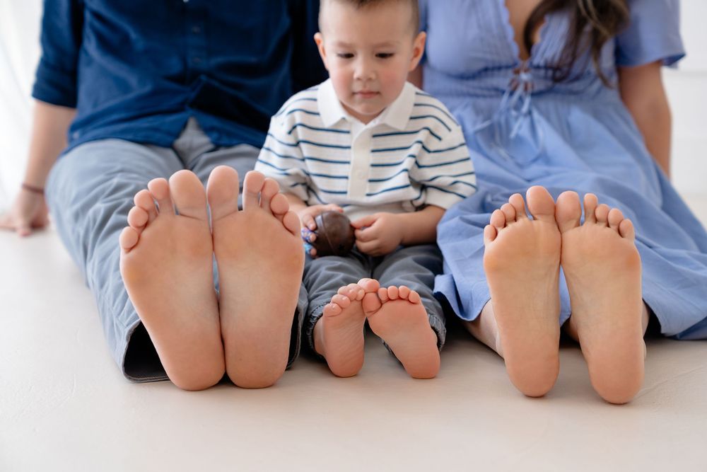 Row of bare feet lined up showing family members sitting together on a white floor.