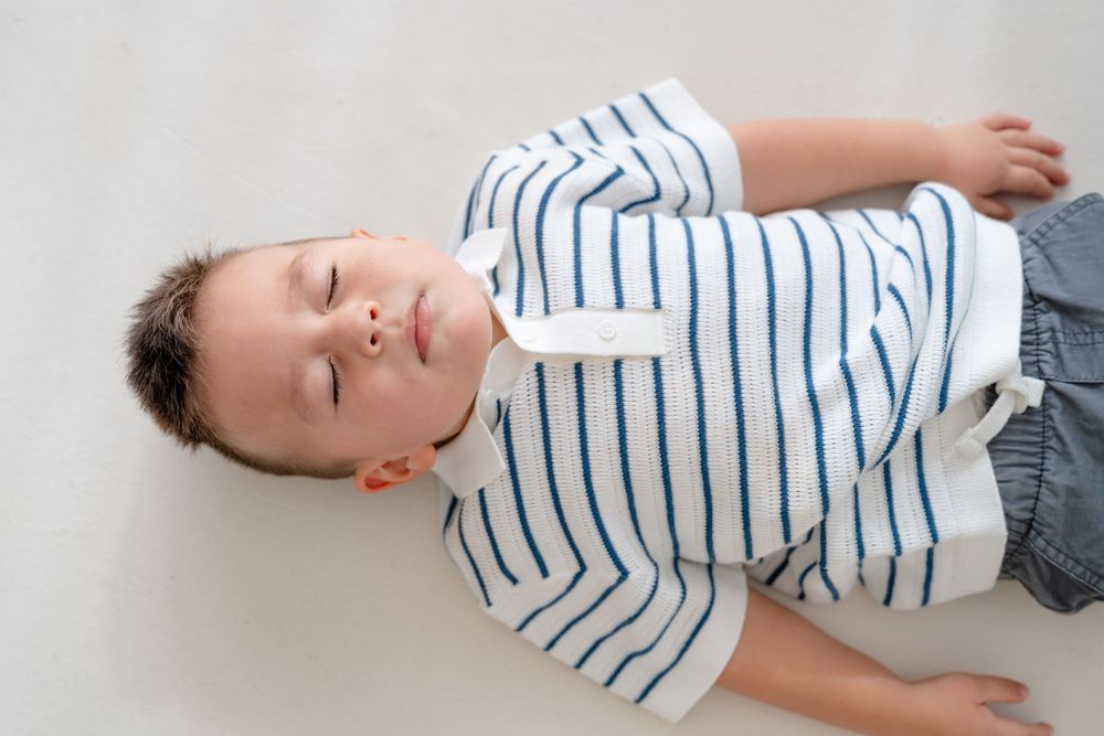 Person in striped shirt and shorts lying on floor in multiple sequential positions showing movement sequence.