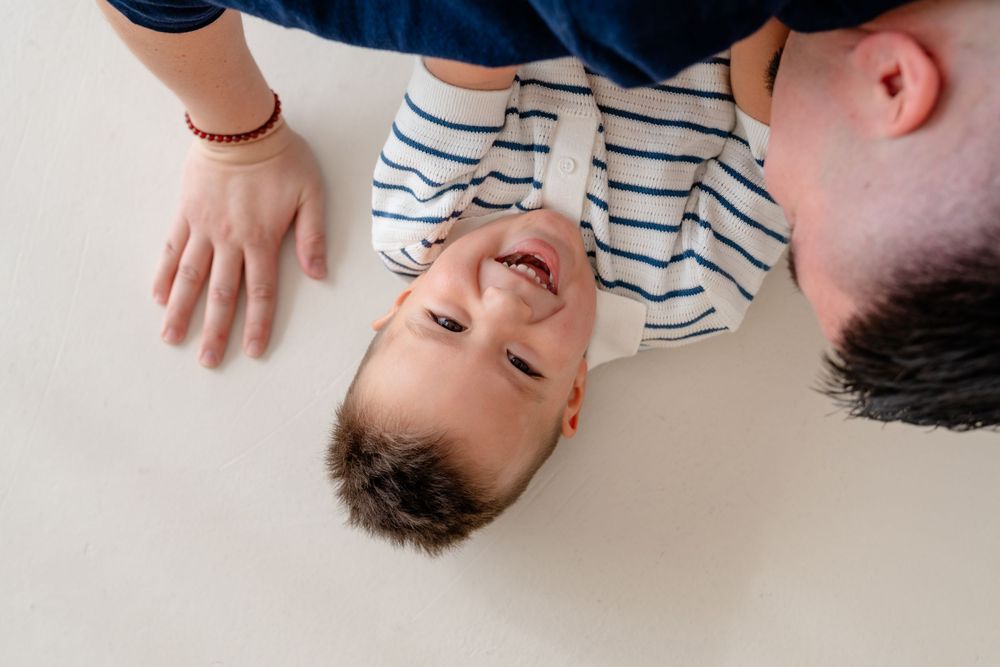 Two people wearing striped shirts lying on a white surface, photographed from above.